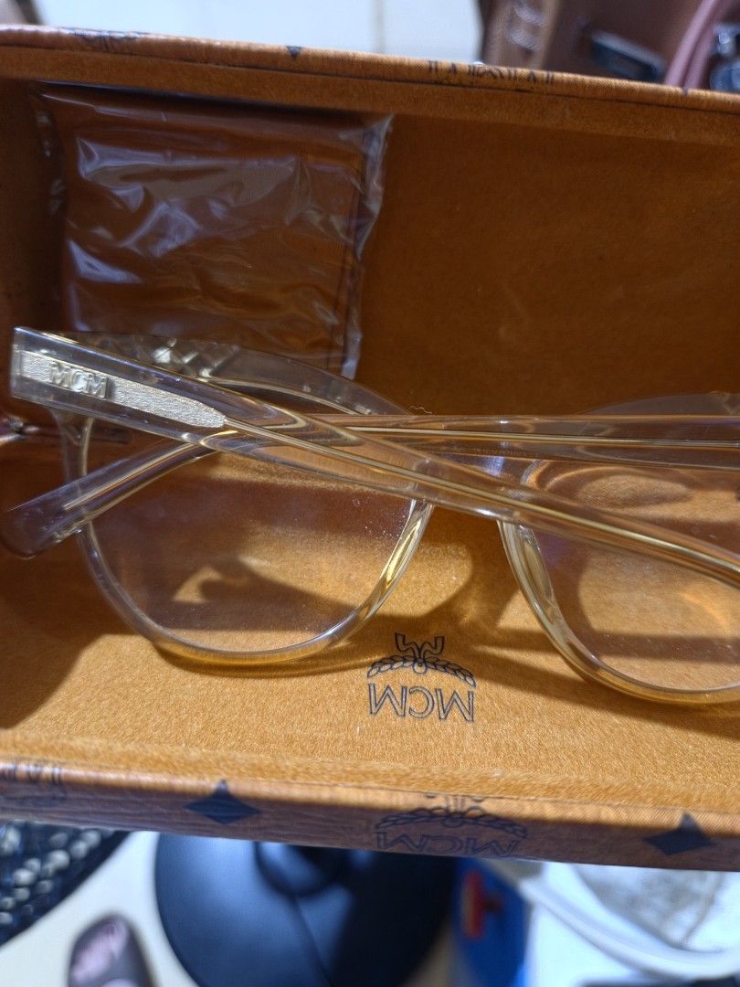 MCM Eyeglasses with Case (Category: Sunglasses & Eyewear) located in Las Pinas. Submitted by swiftdragon_0c099a (Listing ID 1470020646, Image 3). Description: - Authentic clear MCM frames with signature logo on arms - Stylish diamond-textured detailing near the temples - Sturdy construction with a classic, versatile shape - Includes matching signature cognac monogram hard case - Comes with brand new cleaning cloth still wrapped in plastic Swarovs