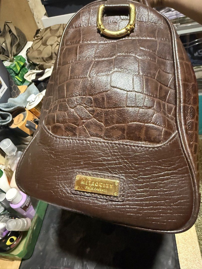 Metrocity Brown Croc-Embossed Leather Handbag (Category: Luxury Bags & Wallets) located in Opol. Submitted by great_finds_kollexion (Listing ID 1469978298, Image 3). Description: - Brand: Metrocity - Color: Dark brown - Material: Croc-embossed leather body with smooth leather base and handles - Hardware: Gold-tone hardware with protective bottom feet and branded zipper pull - Closure: Secure top zip closure - Interior: Features a zip compartment 