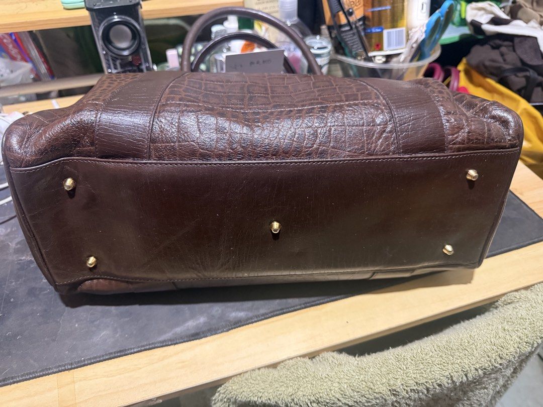 Metrocity Brown Croc-Embossed Leather Handbag (Category: Luxury Bags & Wallets) located in Opol. Submitted by great_finds_kollexion (Listing ID 1469978298, Image 2). Description: - Brand: Metrocity - Color: Dark brown - Material: Croc-embossed leather body with smooth leather base and handles - Hardware: Gold-tone hardware with protective bottom feet and branded zipper pull - Closure: Secure top zip closure - Interior: Features a zip compartment 