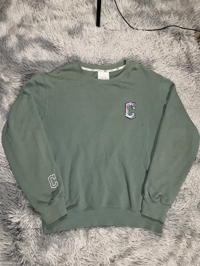 MLB Green Sweatshirt with Graffiti C Logo (Category: Coats, Jackets and Outerwear) located in Muntinlupa City. Submitted by pastforwardthrift (Listing ID 1470126313, Image 1). Description: - Color: Washed sage green - Size: L (Relaxed fit pullover) - Design: Small 'C' logo on chest and right sleeve, large graffiti-style 'C' graphic on the back - Details: Crewneck collar with official MLB branded inner taping and neck tags.