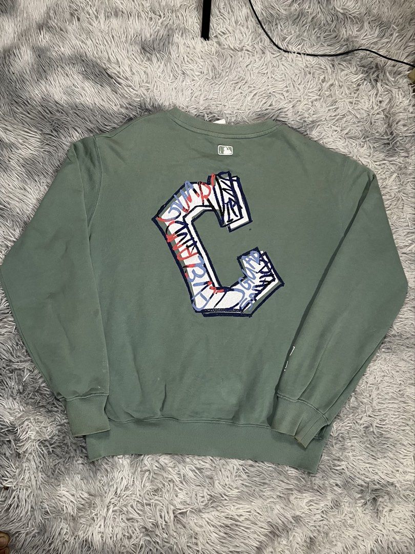MLB Green Sweatshirt with Graffiti C Logo (Category: Coats, Jackets and Outerwear) located in Muntinlupa City. Submitted by pastforwardthrift (Listing ID 1470126313, Image 2). Description: - Color: Washed sage green - Size: L (Relaxed fit pullover) - Design: Small 'C' logo on chest and right sleeve, large graffiti-style 'C' graphic on the back - Details: Crewneck collar with official MLB branded inner taping and neck tags.