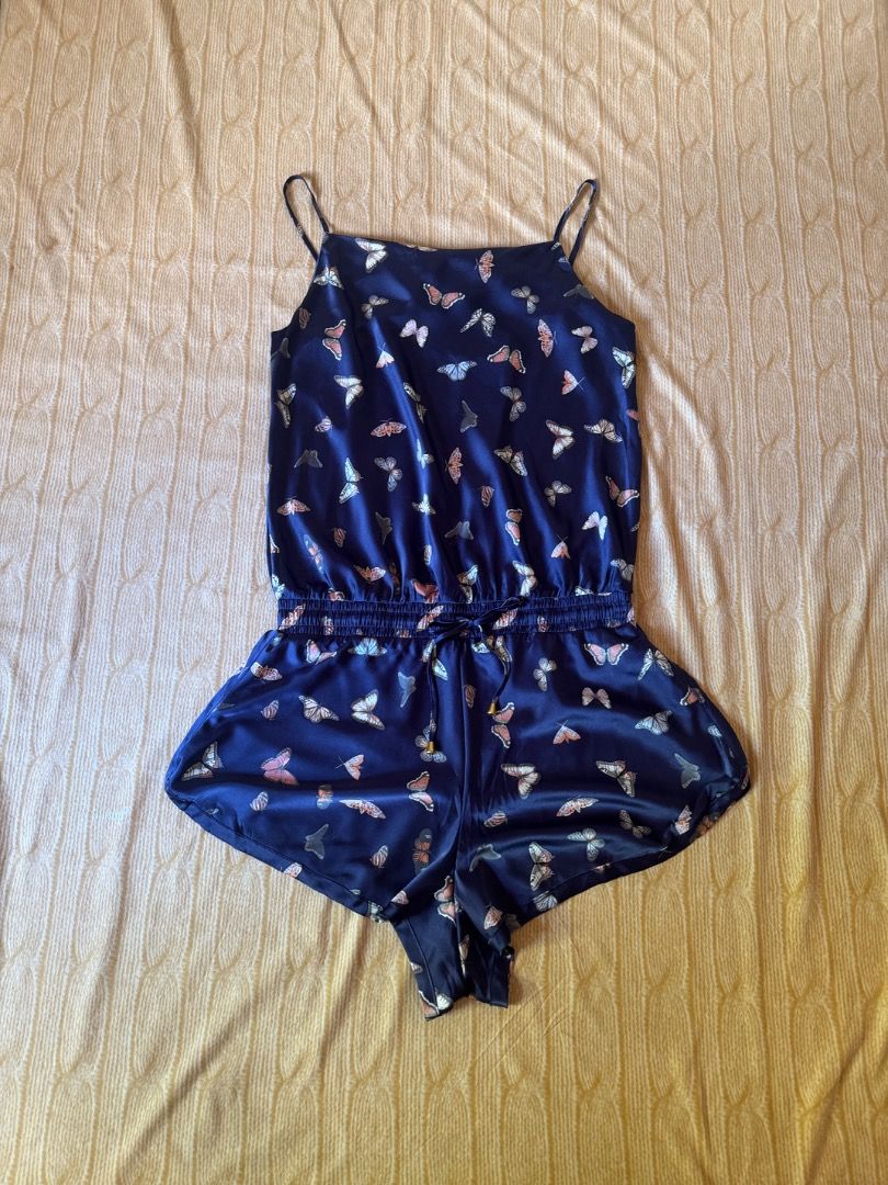 Navy Blue Butterfly Print Cami Romper (Category: Rompers) located in Calasiao. Submitted by clothesbykim (Listing ID 1469995458, Image 1). Description: - Style: Cami romper with a navy blue base and butterfly print - Fit: Size XL with thin adjustable straps and a drawstring waist - Details: Chic gold-tone hardware tips on the drawstring - Fabric: Silky, lightweight satin - Best For: Cozy lounging or sunny weather outings.