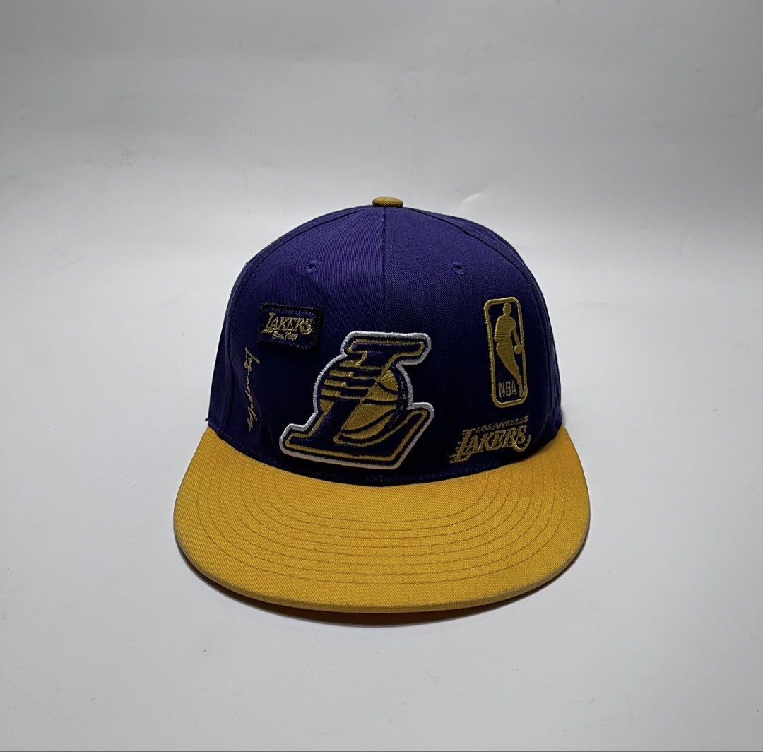 NBA Style LA Lakers Snapback Cap Purple Yellow (Category: Caps & Hats) located in Iloilo. Submitted by fromthebins.ilo2 (Listing ID 1470107111, Image 1). Description: - Authentic NBA Style Los Angeles Lakers snapback hat - Vibrant purple crown with a contrasting yellow brim and top button - Premium embroidered Lakers front logo with collectible team patches on the sides and back - Adjustable black plastic snapback closure for a custom fit - Size: