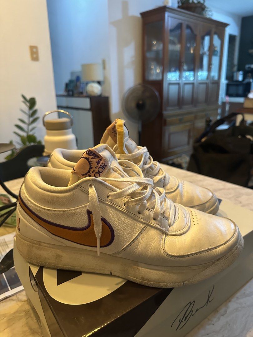 Nike Book 1 Light Orewood Brown (Category: Sneakers) located in Quezon City. Submitted by euanlucas_water (Listing ID 1470078902, Image 1). Description: - Model: Nike Book 1 (Devin Booker signature shoe) - Colorway: White canvas and leather upper with striking orange and purple swoosh - Performance: Equipped with responsive Air Zoom cushioning - Condition: Minor scuffs on midsoles and toe boxes; soles show minimal wear - Inclusions: Complete with