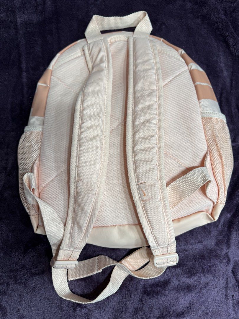 Nike Pink Mini Backpack Just Do It (Category: Backpacks) located in Valenzuela. Submitted by sofiasticated.decluttering (Listing ID 1470071353, Image 2). Description: - Authentic pink Nike mini backpack featuring a classic white swoosh logo - Includes a cute matching rubber 'Just Do It' zipper charm - Handy front zippered pocket, spacious main compartment, and convenient side mesh pockets - Comfortable padded shoulder straps and top haul loop for