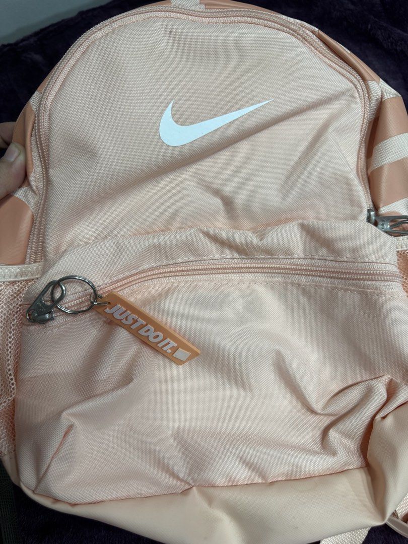 Nike Pink Mini Backpack Just Do It (Category: Backpacks) located in Valenzuela. Submitted by sofiasticated.decluttering (Listing ID 1470071353, Image 3). Description: - Authentic pink Nike mini backpack featuring a classic white swoosh logo - Includes a cute matching rubber 'Just Do It' zipper charm - Handy front zippered pocket, spacious main compartment, and convenient side mesh pockets - Comfortable padded shoulder straps and top haul loop for
