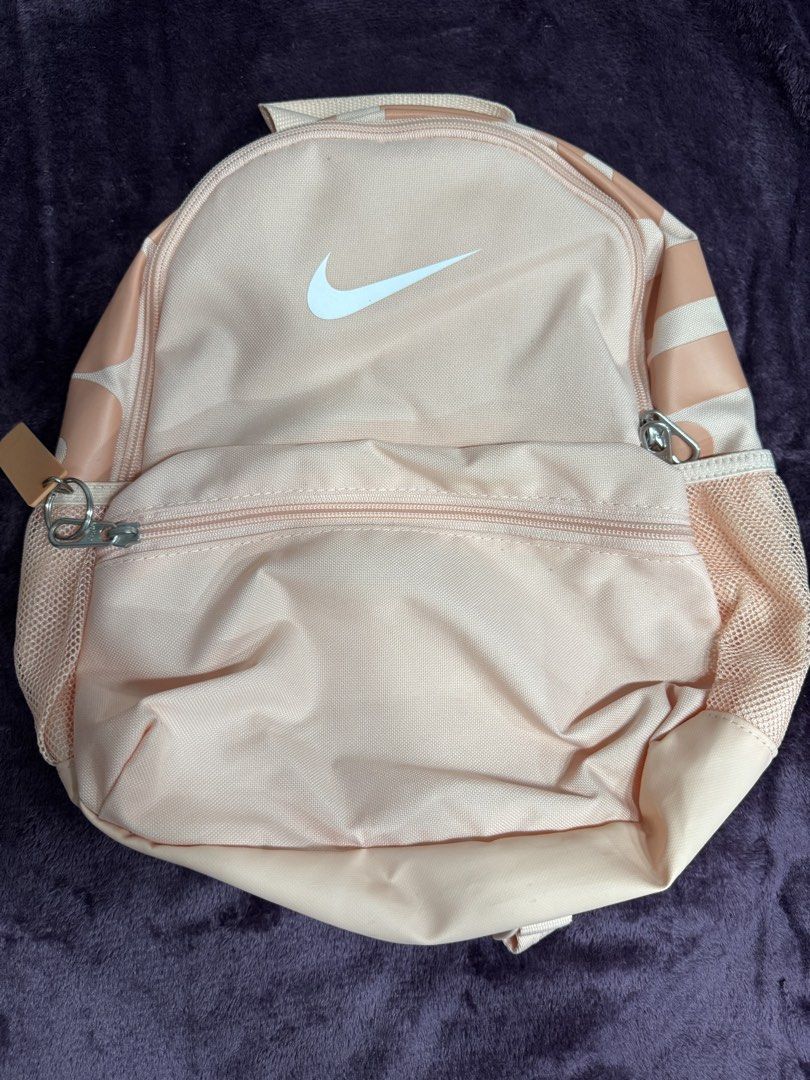 Nike Pink Mini Backpack Just Do It (Category: Backpacks) located in Valenzuela. Submitted by sofiasticated.decluttering (Listing ID 1470071353, Image 1). Description: - Authentic pink Nike mini backpack featuring a classic white swoosh logo - Includes a cute matching rubber 'Just Do It' zipper charm - Handy front zippered pocket, spacious main compartment, and convenient side mesh pockets - Comfortable padded shoulder straps and top haul loop for