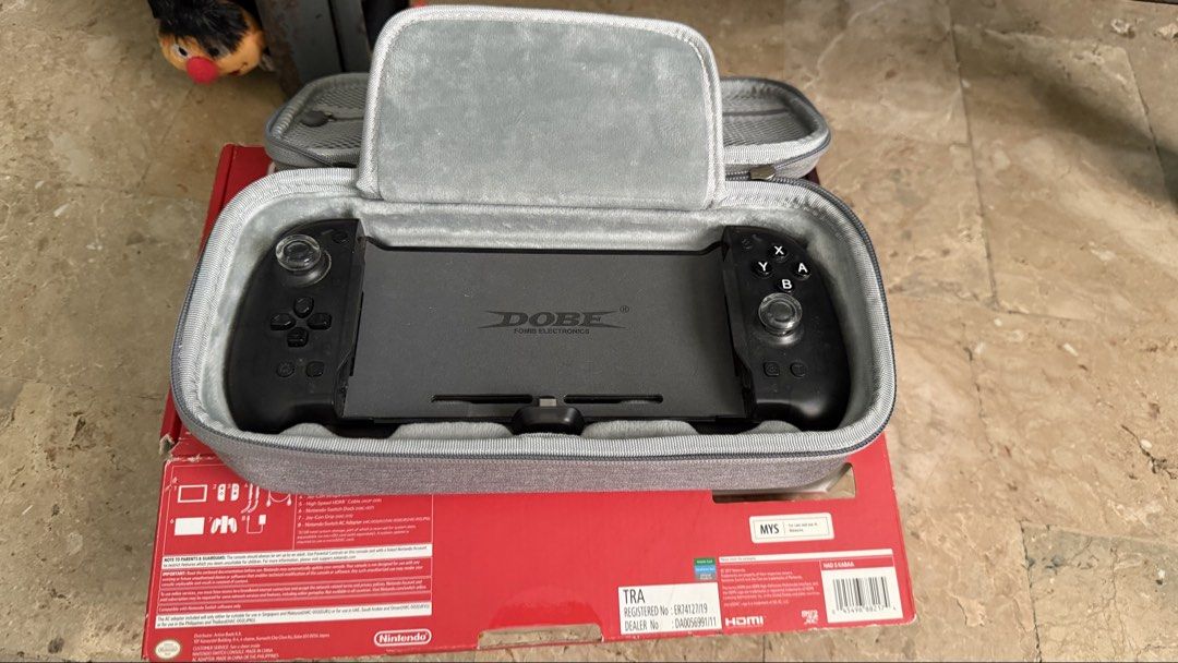 Nintendo Switch Console with Dobe Controller and Case (Category: Nintendo) located in Paranaque City. Submitted by chasanmig (Listing ID 1470054544, Image 2). Description: Fs> Nintendo Switch 1 V2 - Non JB NO JOYCONS Inclusions: - Tablet - Original HDMI - Original Dock - Original Joycon Grips & Straps - Box - Dobe Eggshell (used hard) - Dobe Bag ₱7k Parañaque area Lalamove Ready / Test upon pickup Open for VC.