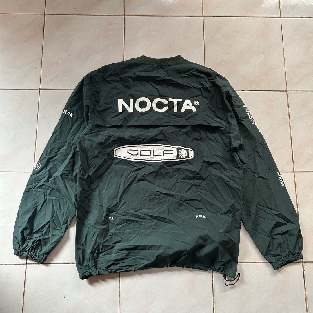 NOCTA Golf Dark Green Windbreaker 🥵 (Category: Coats, Jackets and Outerwear) located in Jinoba-an. Submitted by eegiboy (Listing ID 1470003395, Image 1). Description: - Dark green NOCTA golf windbreaker - Large NOCTA branding and golf graphic on the back - Stylish white text prints on sleeves - Crewneck collar with ribbed detailing - Elastic cuffs and adjustable drawstring hem - Lightweight material, perfect for layering over a tee Wts: Atcon lo
