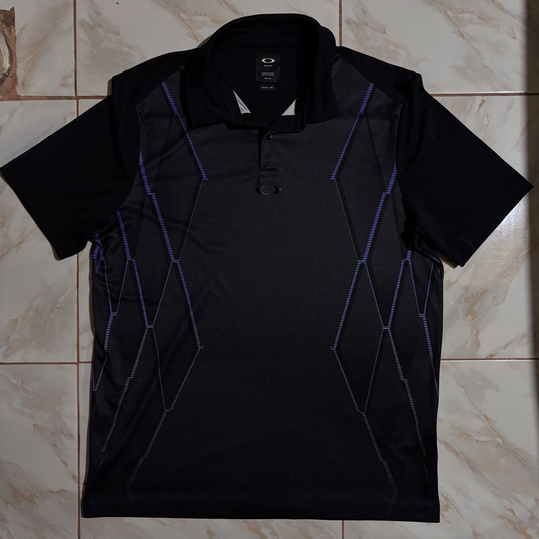Oakley Black Regular Fit Polo Shirt (Category: Tshirts & Polo Shirts ) located in Dumaguete. Submitted by revillahar03975 (Listing ID 1469982442, Image 1). Description: - Brand: Oakley - Style: Regular fit polo shirt with short sleeves and standard collar - Color: Black with purple geometric stripe accents - Details: Single button placket with signature Oakley ellipse hardware loop - Size: L .