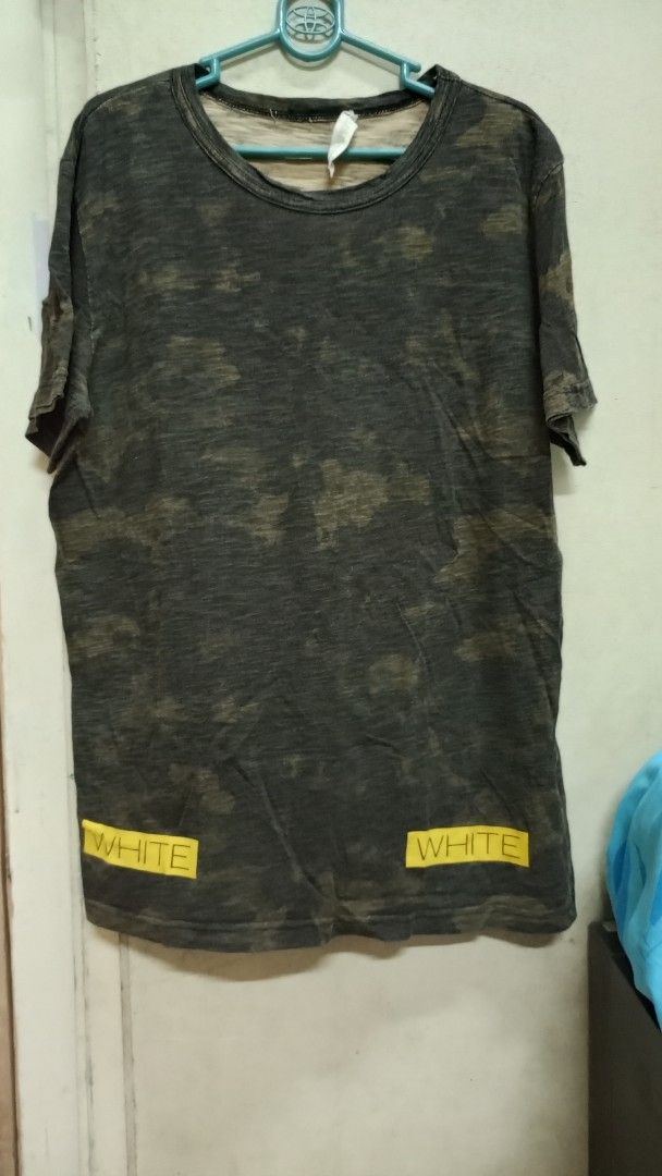 Off-White Camouflage Yellow Diagonal Print T-shirt (Category: Tshirts & Polo Shirts ) located in Manila. Submitted by rizu09 (Listing ID 1470040486, Image 2). Description: - Brand: Off-White - Item: Camo Tee - Size: Large (L) - Color/Wash: Dark grey and green camouflage - Details: Distressed collar and hems, big yellow box logo on upper back, diagonal stripes on lower back, small yellow text blocks near front hem - Material: Premium wool, polyest