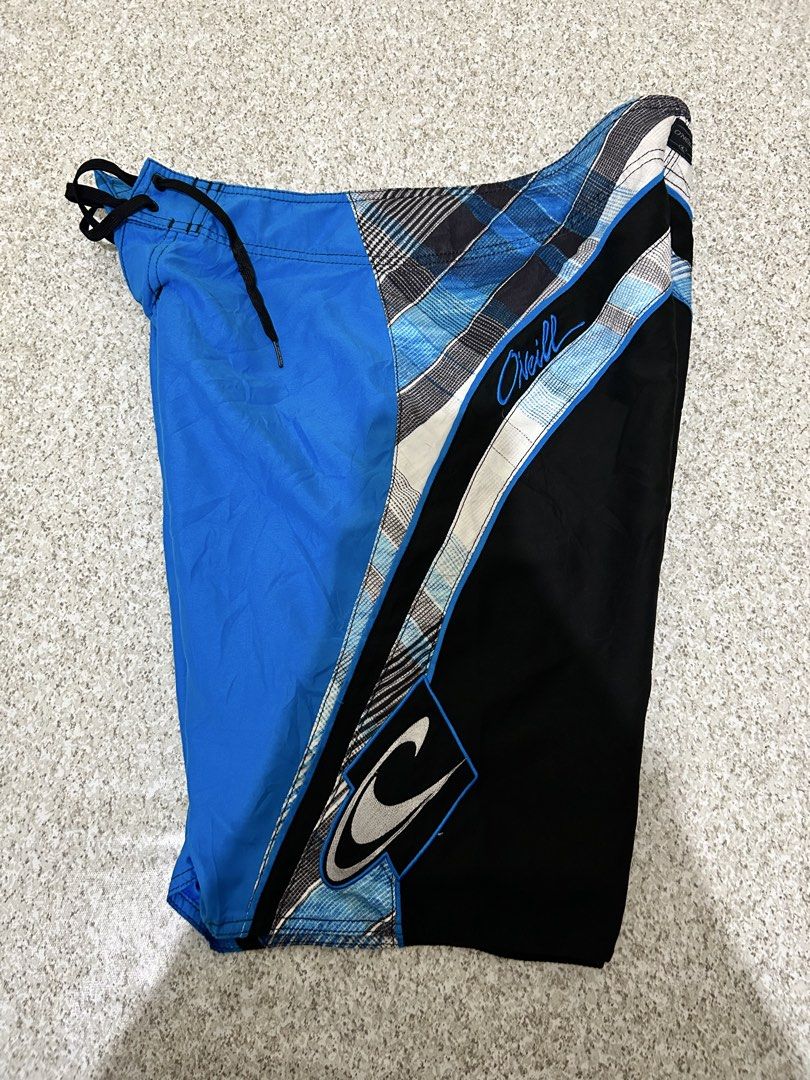 O'Neill Board Shorts Blue Black Plaid (Category: Swim Trunks & Board Shorts) located in Angeles City. Submitted by johngamboa (Listing ID 1469951230, Image 1). Description: - Brand: O'Neill - Style: Classic surf board shorts - Design: Blue, black, and white plaid with vibrant colorblocking - Waist: Drawstring closure with black cords - Pockets: Side pocket with flap and key loop detail - Branding: Embroidered O'Neill script logo on the back and s