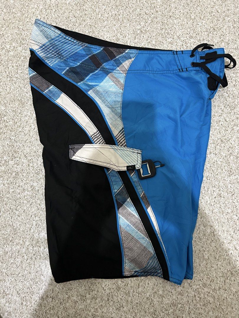O'Neill Board Shorts Blue Black Plaid (Category: Swim Trunks & Board Shorts) located in Angeles City. Submitted by johngamboa (Listing ID 1469951230, Image 2). Description: - Brand: O'Neill - Style: Classic surf board shorts - Design: Blue, black, and white plaid with vibrant colorblocking - Waist: Drawstring closure with black cords - Pockets: Side pocket with flap and key loop detail - Branding: Embroidered O'Neill script logo on the back and s
