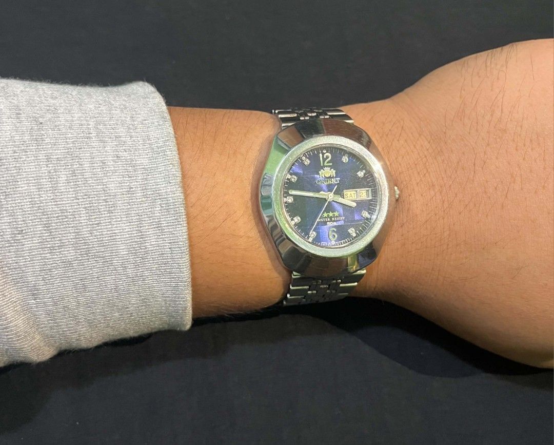 Orient 3 Star Blue Dial Automatic Watch (Category: Men's Watches) located in Cebu City. Submitted by jbok_watches. (Listing ID 1470101454, Image 2). Description: - Brand/Model: Vintage Orient 3 Star Automatic Watch - Dial: Striking blue patterned dial with crystal hour markers and 12/6 digits - Case & Strap: Silver stainless steel case and matching bracelet with signed logo clasp - Features: Day and date window at the 3 o'clock position - Movemen