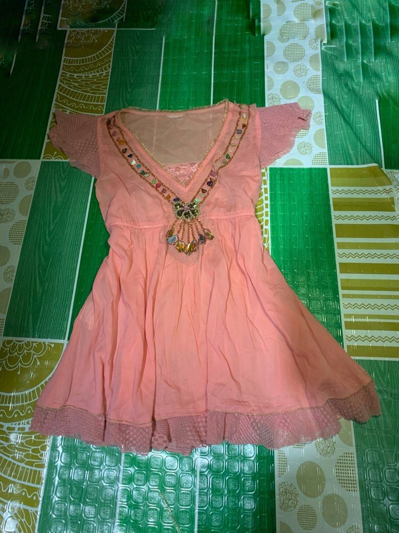 Pink Beaded V-Neck Mini Dress (Category: Dresses) located in Cebu City. Submitted by selamethrift (Listing ID 1470061928, Image 1). Description: - Color: Peach-pink - Style: Short dress with a flattering empire waistline and flared skirt - Neckline: V-neck detailed with colorful beads and stones - Sleeves & Hem: Short lace sleeves and matching lace trim at the bottom - Extra Details: Inner mesh layer at the chest with lace accent, lightweight fab