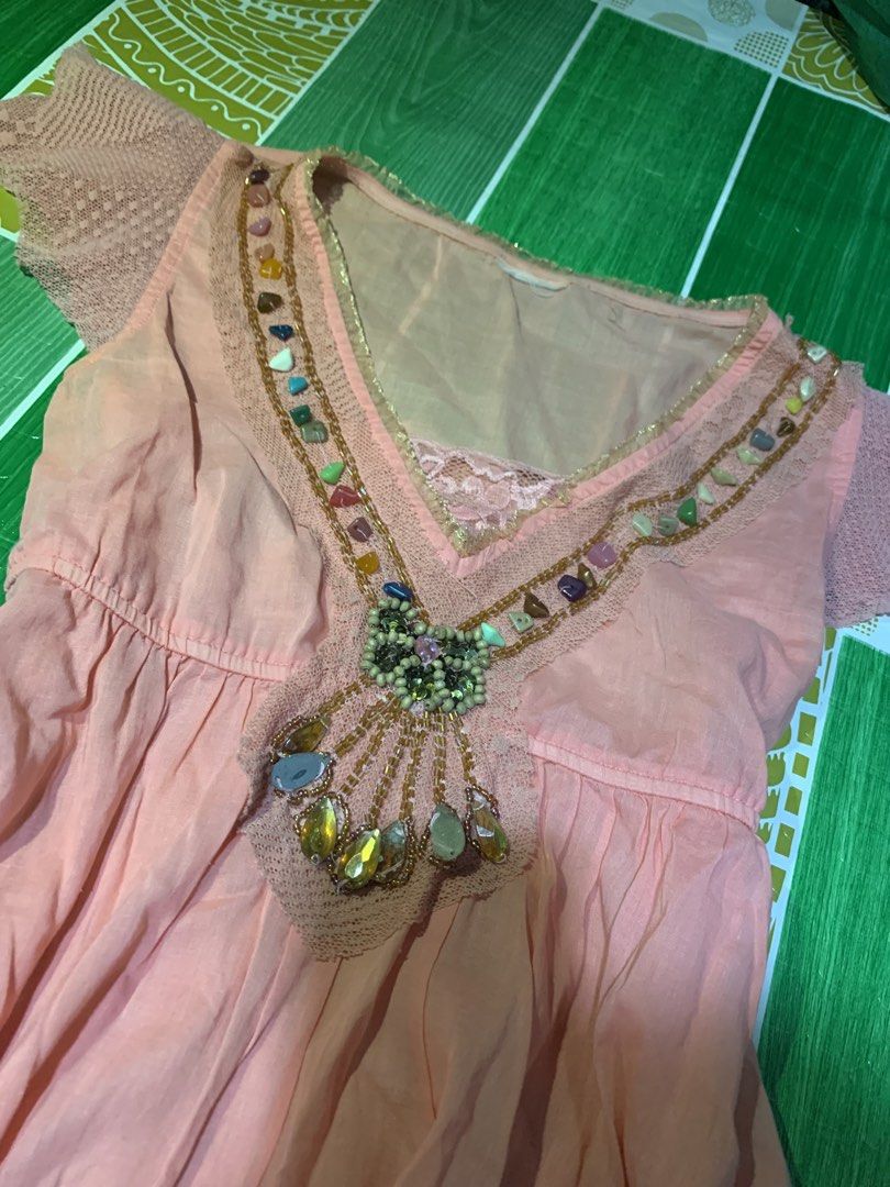 Pink Beaded V-Neck Mini Dress (Category: Dresses) located in Cebu City. Submitted by selamethrift (Listing ID 1470061928, Image 2). Description: - Color: Peach-pink - Style: Short dress with a flattering empire waistline and flared skirt - Neckline: V-neck detailed with colorful beads and stones - Sleeves & Hem: Short lace sleeves and matching lace trim at the bottom - Extra Details: Inner mesh layer at the chest with lace accent, lightweight fab