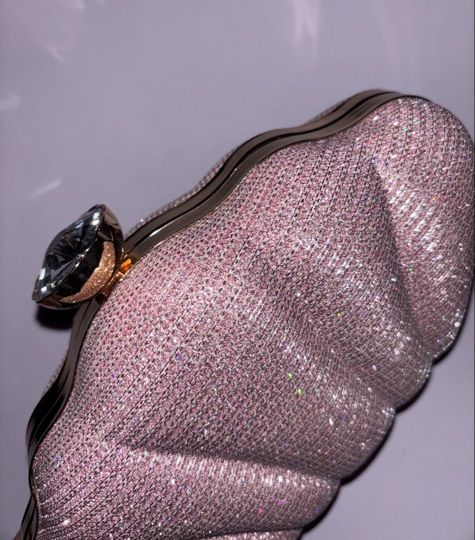 Pink glitter evening clutch with crystal clasp (Category: Clutches) located in Manila. Submitted by chn.ph (Listing ID 1469994651, Image 3). Description: 🐚 Color & Finish: Sparkly pink hard shell with all-over pleated texture 🧜‍♀️ Interior: Black fabric lining with enough space for your cards and lipstick 🪸Occasion: Ideal evening bag for weddings, parties, or dinner dates (Note: Used only once, but the metal chain strap is missing.).