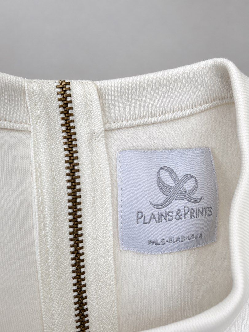 Plains & Prints White Sleeveless Top with Ruffles (Category: Sleeveless) located in Cabanatuan. Submitted by yass03_loved (Listing ID 1469976585, Image 2). Description: - Brand: Plains & Prints - Color: White - Style: Sleeveless top with round neckline and exposed gold back zipper - Detail: Contrasting white ruffled panels along both sides - Condition: Clean, crisp, and well-maintained - Fit/Styling: Minimalist design, easy to pair with high-wais