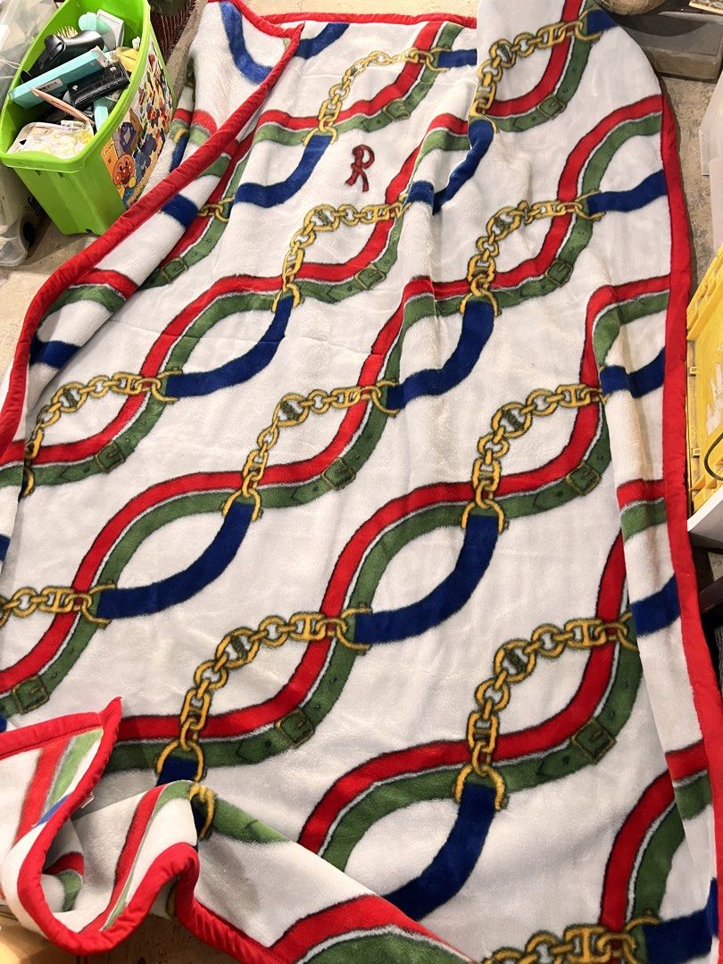 Plush Blanket with Chain and Belt Pattern (Category: Bedding & Towels) located in Manila. Submitted by suarezbaby04975 (Listing ID 1469973734, Image 1). Description: - Size: Large, covers a bed nicely - Material: Soft and warm fleece, perfect for cold nights - Design: Repeating intertwined chains and multicolored straps (red, blue, green) on a white background with a bold red border - Condition: Kept neatly folded in storage, well-maintained.