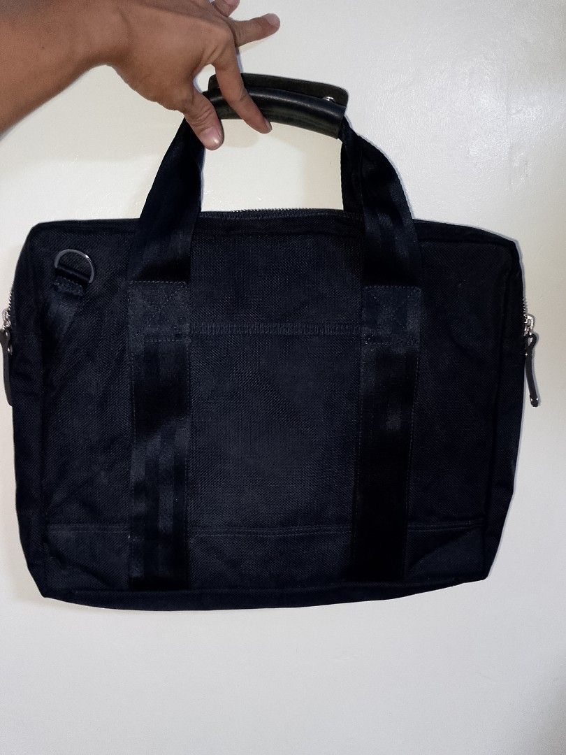 Porter International Black Nylon Briefcase Bag (Category: Briefcases) located in Manila. Submitted by mjthrifted_second (Listing ID 1469983655, Image 2). Description: - Brand: Porter International - Color: Solid black - Material: Durable nylon with leather handle wrap - Exterior: Multiple front zippered pockets, metal D-rings, and utility webbing straps - Interior: Red, navy, and white striped fabric lining with organizer pockets - Details: Signa