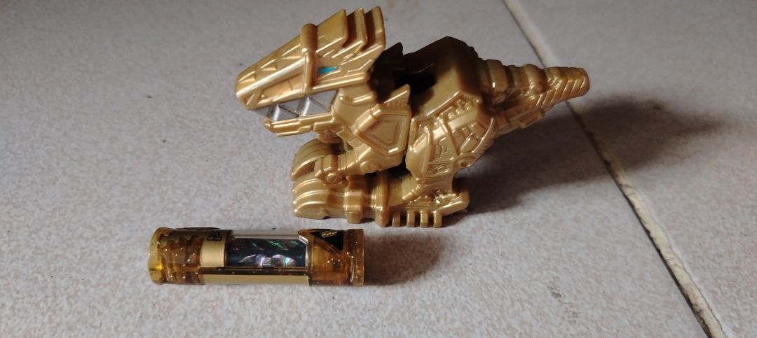 Poweranger Dino charger (Category: Kids Toys) located in Caloocan City. Submitted by mysticrabbit_c00da6 (Listing ID 1470119389, Image 2). Description: - Gold plastic dinosaur figure inspired by Power Rangers Dino Charge - Includes removable battery component - Stands nicely on its own - Great collectible piece for fans of the series - Clean condition with no major scuffs or damage - Ready for display or play.
