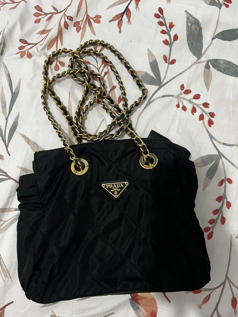 Prada Quilted Nylon Chain Shoulder Bag Black (Category: Luxury Bags & Wallets) located in Antipolo. Submitted by cdro627734 (Listing ID 1470083633, Image 1). Description: - Authentic Prada shoulder bag in classic black quilted nylon - Features the iconic metal triangle logo on the front - Elegant gold-tone hardware paired with black leather-woven chain straps - Secure top zipper closure to keep your belongings safe - Roomy interior fits all your 