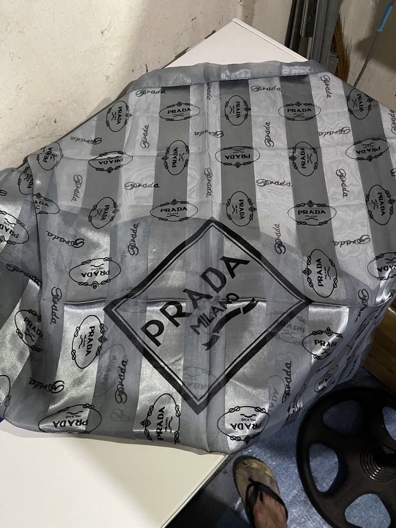 Prada Striped Silk Scarf Grey (Category: Luxury Accessories) located in Mandaluyong City. Submitted by mark2pac (Listing ID 1470054098, Image 2). Description: - Authentic Prada grey and silver striped scarf - Features repeating Prada Milano logo print and large center diamond graphic - Lightweight material with a smooth texture - Versatile size, perfect for styling around the neck or bag - Clean fabric with no pulls or stains - Sourced from a smo