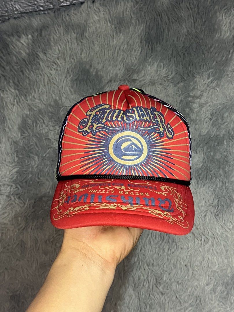 Quiksilver Red Graphic Trucker Cap with Multi-color Mesh (Category: Caps & Hats) located in Muntinlupa City. Submitted by pastforwardthrift (Listing ID 1470125873, Image 2). Description: - Brand: Quiksilver - Color: Red with black mesh back - Design: Large front graphic logo with sunburst artwork and colourful vertical stripes on the back - Closure: Adjustable snapback - Condition: Clean brim, structured front panels, and interior tag intact.