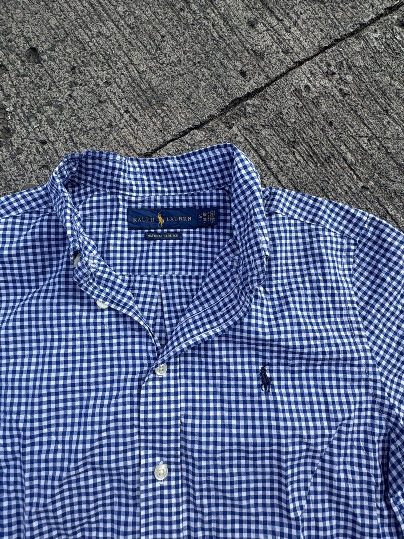 Ralph Lauren Blue Gingham Short Sleeve Button-Down Shirt (Category: Tshirts & Polo Shirts ) located in Iligan City. Submitted by seddicmoti2002 (Listing ID 1470138910, Image 2). Description: Ralph Lauren button-down shirt in blue and white gingham check pattern. Short sleeves, classic collar, and front button closure. Small embroidered pony logo on the left chest. Tag reads size L (14-16) with natural stretch fabric. 100 percent cotton, made in V