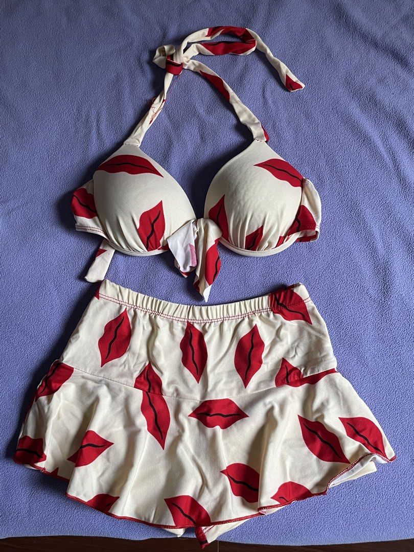 Red Lips Print Halter Bikini and Skirt Set (Category: Bikinis & Swimsuits) located in Antipolo. Submitted by chicgrc (Listing ID 1469967188, Image 1). Description: - Style: Two-piece swimwear set - Design: Playful red lips pattern on off-white background - Top: Halter style with molded push-up cups and cute front tie detail - Bottom: High-waisted with an attached mini skirt for extra coverage - Material: Soft and stretchy fabric for all-day comfo
