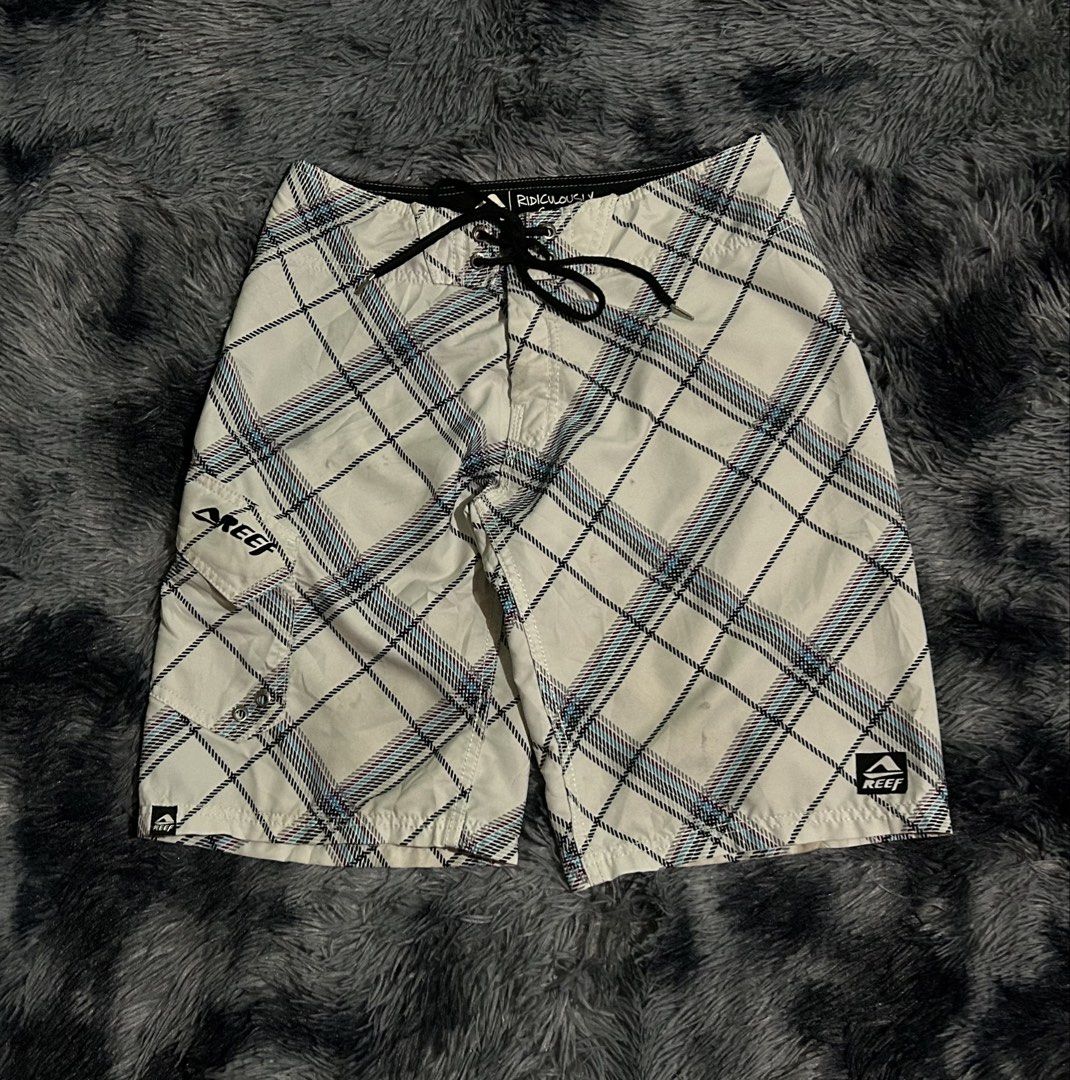 Reef Plaid Board Shorts Packable Size 31 W15 L21 (Category: Swim Trunks & Board Shorts) located in Cadiz. Submitted by jaybatiller (Listing ID 1470051548, Image 1). Description: - Brand: Reef - Style: Board shorts in white plaid with blue and purple stripes - Size: 31 waist - Material: 100% quick-dry polyester - Features: Front drawstring closure, right-leg cargo pocket with Reef logo, and small hem tag - Care: Hand wash only - Condition: Ready f