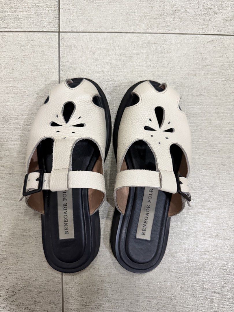 Renegade Folk Mules (Size 8) (Category: Flats & Sandals) located in Davao. Submitted by pamdyclutters (Listing ID 1470072165, Image 1). Description: - Brand: Renegade Folk - Size: US 8 / PH equivalent - Color: White leather with chunky black soles - Features: Floral cutout upper strap and adjustable side buckle for secure fit - Traction: Grooved soles for anti-slip grip - Condition: Excellent, minimal wear on soles and footbeds.
