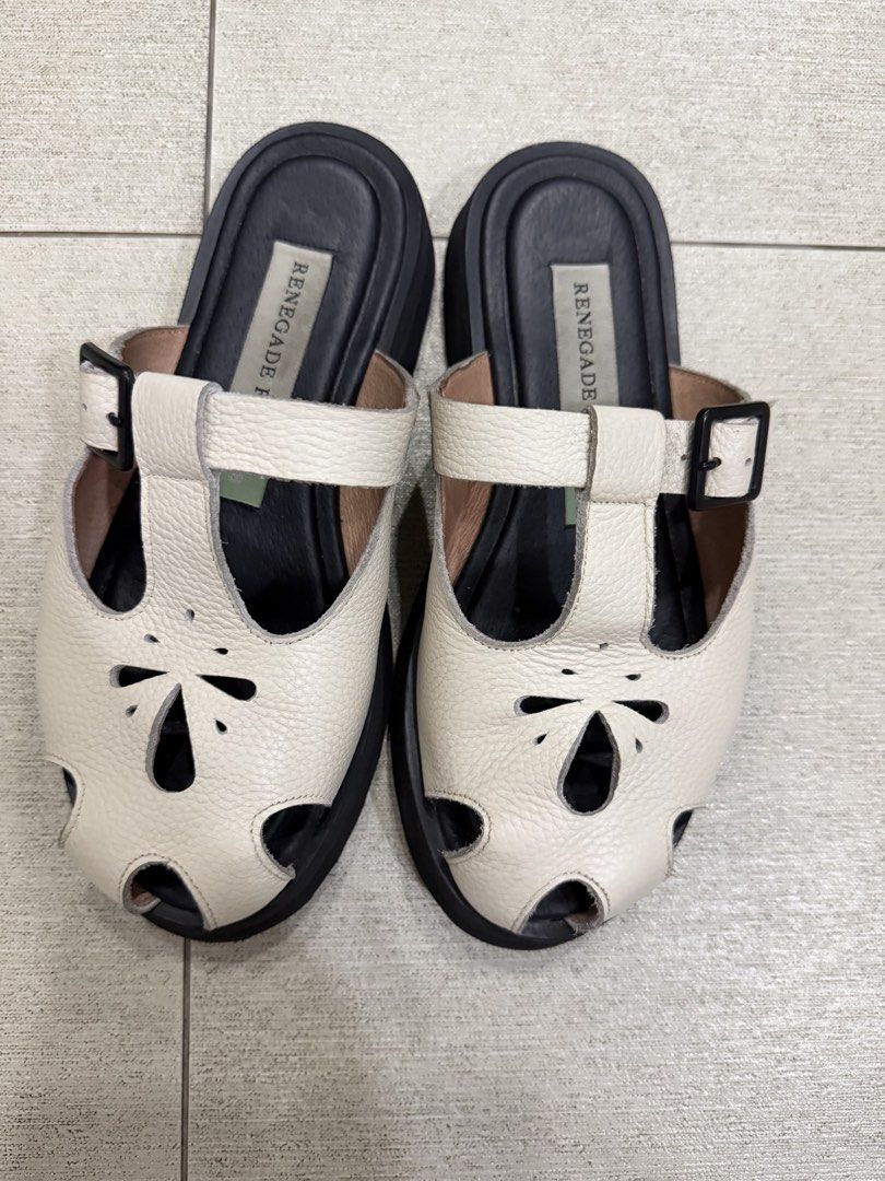 Renegade Folk Mules (Size 8) (Category: Flats & Sandals) located in Davao. Submitted by pamdyclutters (Listing ID 1470072165, Image 2). Description: - Brand: Renegade Folk - Size: US 8 / PH equivalent - Color: White leather with chunky black soles - Features: Floral cutout upper strap and adjustable side buckle for secure fit - Traction: Grooved soles for anti-slip grip - Condition: Excellent, minimal wear on soles and footbeds.