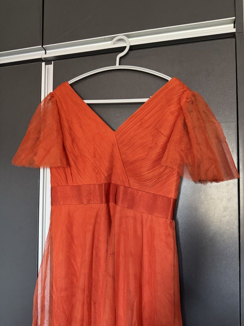 Rusty Orange Dress Gown Flared Sleeves (Category: Dresses) located in Dasmarinas. Submitted by akelvin23 (Listing ID 1470112373, Image 3). Description: - Style: V-neck maxi dress with flowy tulle skirt overlay - Color: Vibrant orange - Details: Pleated bodice, sheer flared sleeves, and satin waistband - Closure: Concealed back zipper - Condition: Worn once, dry-cleaned, no stains or tears Waist - 29 in Shoulder - 15.5 in Bust - 33 in approx Lengt