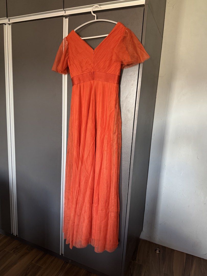 Rusty Orange Dress Gown Flared Sleeves (Category: Dresses) located in Dasmarinas. Submitted by akelvin23 (Listing ID 1470112373, Image 2). Description: - Style: V-neck maxi dress with flowy tulle skirt overlay - Color: Vibrant orange - Details: Pleated bodice, sheer flared sleeves, and satin waistband - Closure: Concealed back zipper - Condition: Worn once, dry-cleaned, no stains or tears Waist - 29 in Shoulder - 15.5 in Bust - 33 in approx Lengt