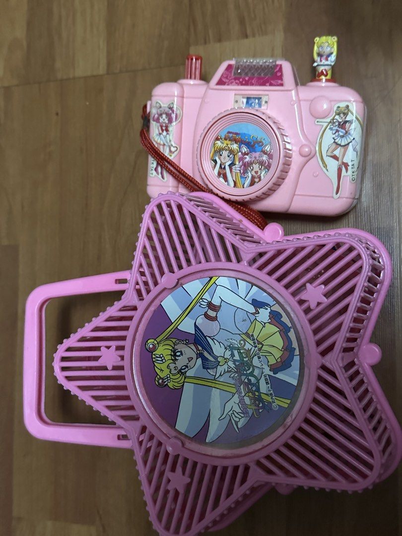 Sailor Moon figures, purses, camera, and star fan bundle (Category: Figurines & Statues) located in Del Monte. Submitted by valin. (Listing ID 1469979399, Image 2). Description: - Massive Sailor Moon collection for fans and collectors - Includes mini chibi figures with stands (Sailor Moon, Mercury, Mars, Venus, Jupiter, and Chibi Moon) - Comes with 2 cute heart pouches - Includes a pink toy camera decorated with stickers - Features a star-shaped 