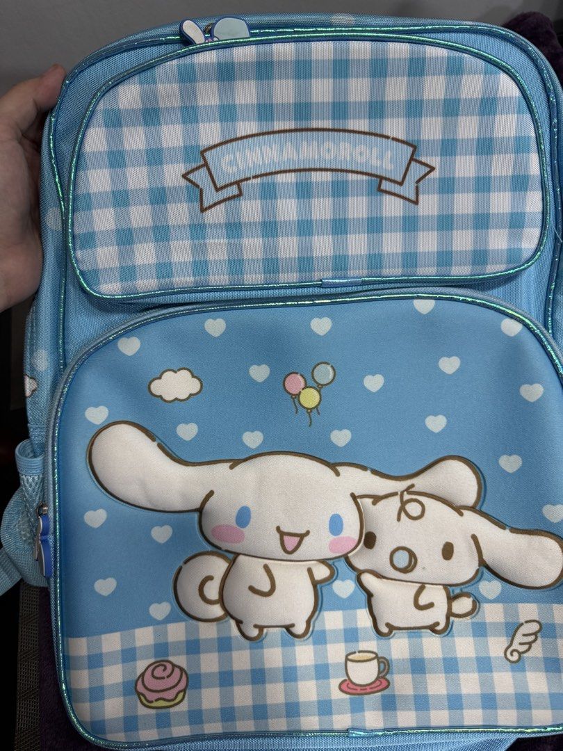 Sanrio Cinnamoroll Light Blue Gingham Backpack (Category: Backpacks) located in Valenzuela. Submitted by sofiasticated.decluttering (Listing ID 1470070500, Image 3). Description: - Official 2024 Sanrio Cinnamoroll merchandise - Charming light blue color with a cute gingham pattern on the top pocket and bottom front - Adorable graphic featuring Cinnamoroll and friends on the front - Comfortable, adjustable straps matching the gingham design - Secu