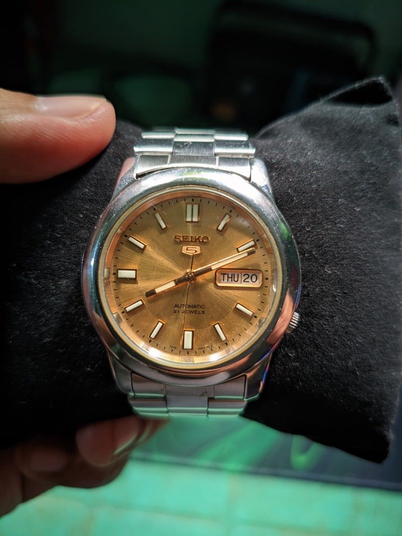 Seiko 5 automatic (Category: Luxury Watches) located in Makati City. Submitted by ointtt (Listing ID 1469966865, Image 2). Description: timeless classic featuring a stunning champagne/gold sunburst dial, sharp lumed hands, and the signature day-date window at 3 o'clock. Brand: Seiko 5 Movement: Automatic (21 Jewels) Dial: Champagne Sunburst with Applied Gold Baton Markers Functions: Complication Case/Bracelet: Stainless Steel.