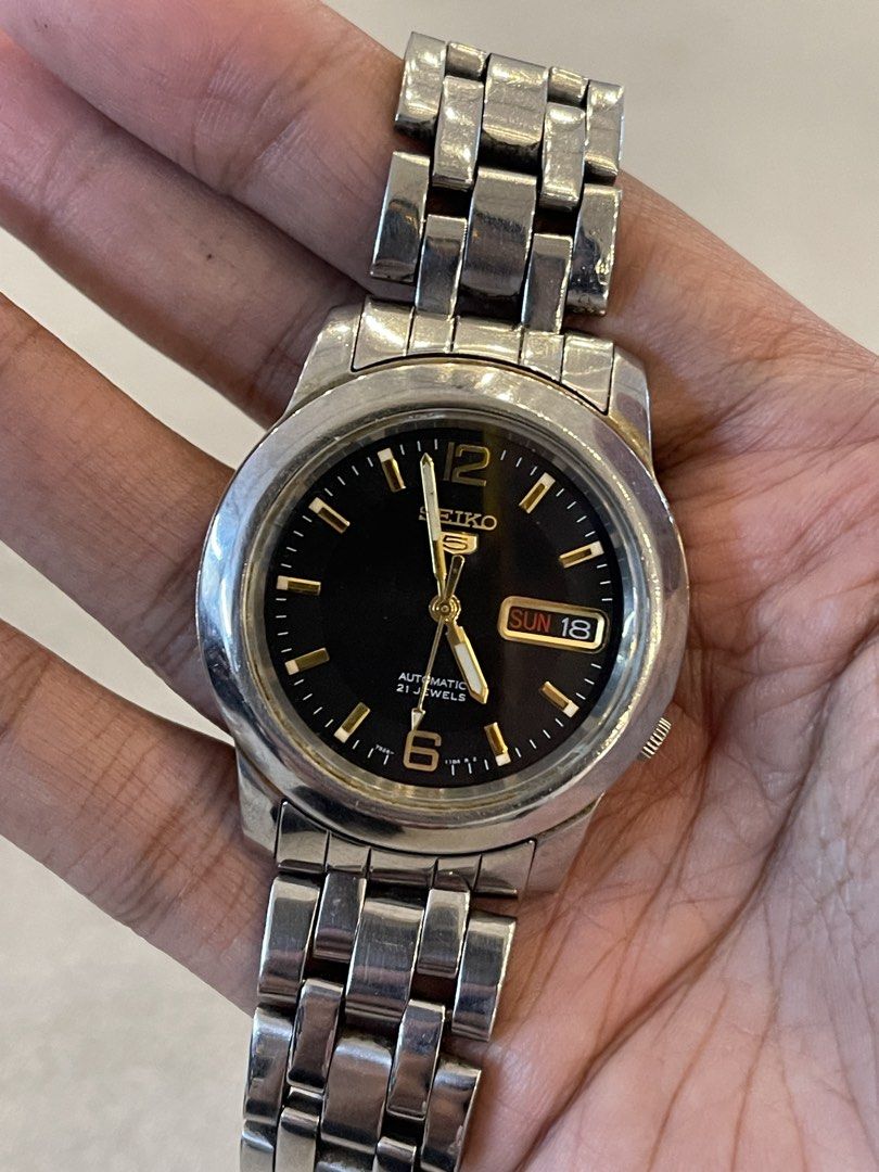 Seiko 5 Automatic 21 Jewels Black Dial Watch (Category: Men's Watches) located in Manila. Submitted by missme1207 (Listing ID 1470059974, Image 1). Description: - Brand: Seiko 5 Automatic - Movement: Reliable 7S26 automatic movement with exhibition case back - Dial: Black dial with elegant gold-tone hands and markers - Features: Convenient day and date window at the 3 o'clock position - Bracelet: Stainless steel link bracelet with signed deployan
