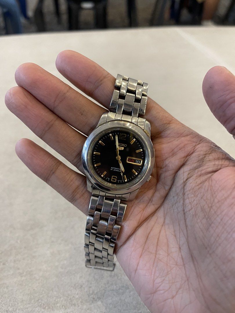 Seiko 5 Automatic 21 Jewels Black Dial Watch (Category: Men's Watches) located in Manila. Submitted by missme1207 (Listing ID 1470059974, Image 2). Description: - Brand: Seiko 5 Automatic - Movement: Reliable 7S26 automatic movement with exhibition case back - Dial: Black dial with elegant gold-tone hands and markers - Features: Convenient day and date window at the 3 o'clock position - Bracelet: Stainless steel link bracelet with signed deployan