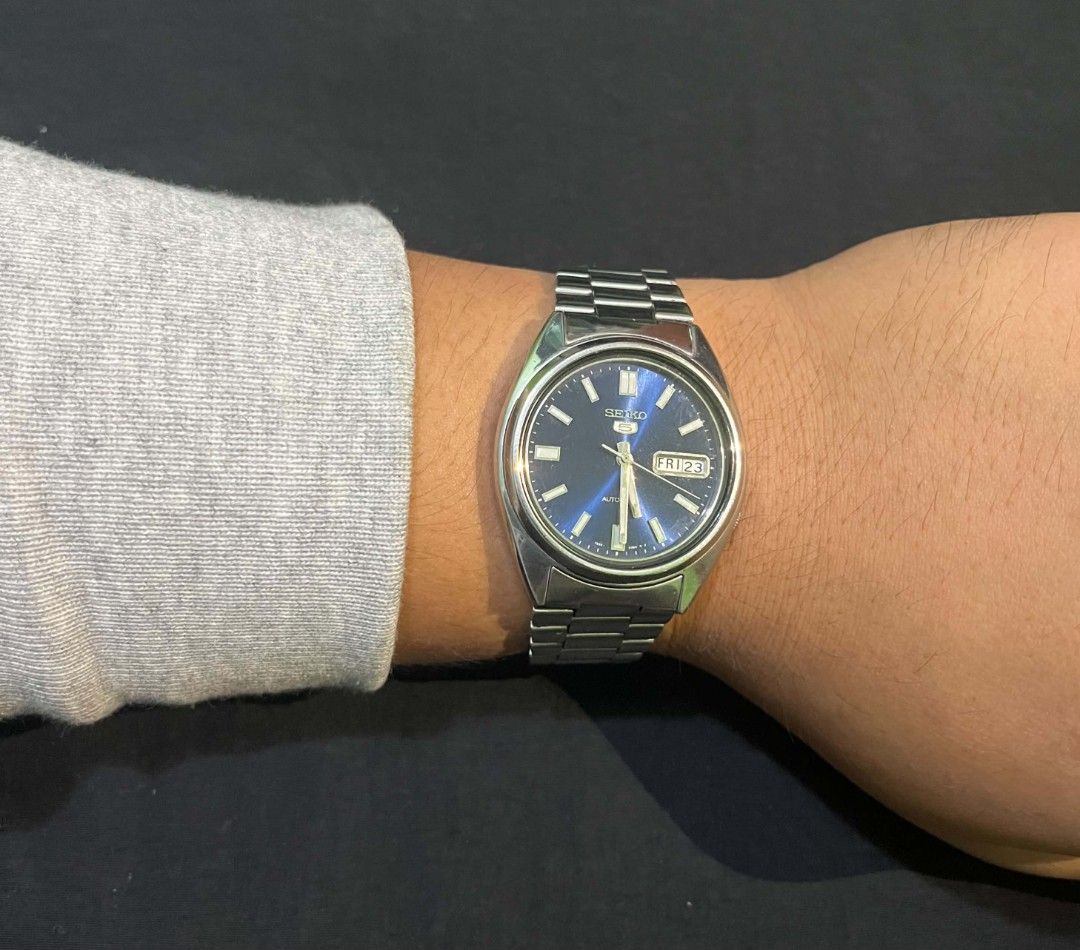 Seiko 5 Automatic Blue Dial Watch (Category: Men's Watches) located in Cebu City. Submitted by jbok_watches. (Listing ID 1470101133, Image 2). Description: - Brand: Seiko 5 Automatic Watch - Dial: Striking blue sunburst dial with 3 o'clock day/date window - Material: Stainless steel case and matching metal bracelet with signed clasp - Movement: Automatic movement visible through the exhibition case back - Condition: Classic everyday timepiece wit