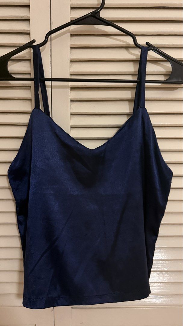 [Self-Tie Back] Navy Blue Satin V-Neck Tie-Back Cami Top (Category: Sleeveless) located in Quezon City. Submitted by oliviablanche (Listing ID 1470112850, Image 1). Description: - Size: Free size - Color: Navy Blue - Neckline: Soft V-neckline with thin shoulder straps a Details: Smooth satin-like fabric with a subtle sheen, relaxed silhouette, straight hem, and self-tie bow detail at the back - Styling: Versatile and elegant, easy to dress up wit