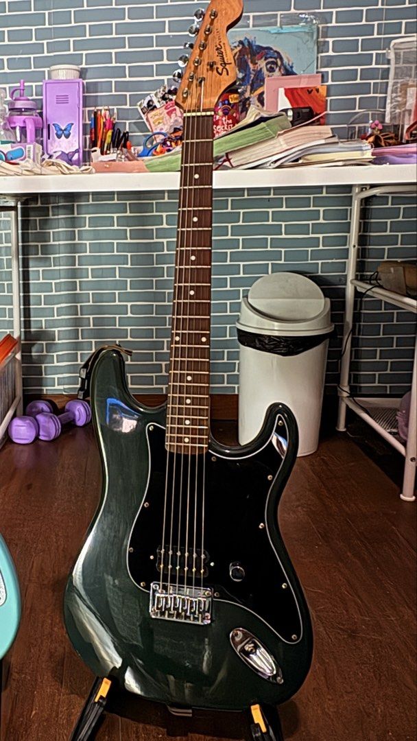 Squier Bullet Stratocaster Electric Guitar (Category: Musical Instruments) located in Quezon City. Submitted by robinjamesmedina (Listing ID 1470080205, Image 2). Description: - Model: Squier Bullet Stratocaster Electric Guitar - Finish: Dark green (originally baltic blue but faded due to age and clear finish yellowing) - Pickups: Single humbucker alnico v copy. layout for a punchy, straightforward rock tone - Hardware: Hardtail tiploader bridge 