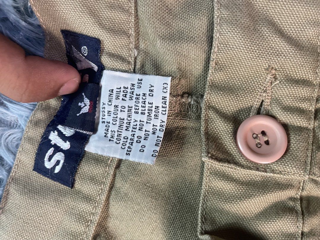 Stussy Khaki Cargo Shorts Size 36 (Category: Shorts) located in Manila. Submitted by jssur (Listing ID 1470083976, Image 3). Description: - Brand: Stussy - Item: Khaki Cargo Shorts - Size: 36 - Made in: China - Fit: Relaxed streetwear fit - Details: Button fly with pinkish button closure, multiple side and back cargo pockets, double knee panels - Branding: Stussy interior waistband tag and small logo tag near pocket.