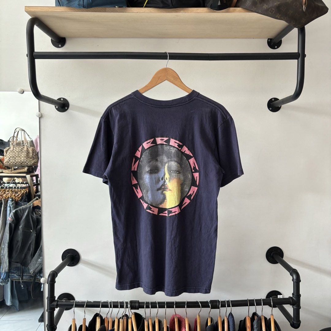 Supreme Navy Graphic T-Shirt Medium (Category: Tshirts & Polo Shirts ) located in Bambang. Submitted by heats777 (Listing ID 1470018760, Image 3). Description: - Brand: Supreme - Color: Navy blue (slightly faded, lived-in look) - Size: Medium - Material: Pre-shrunk cotton - Design: Small circular graphic on front left chest; large face graphic inside a pink circular text frame on the back - Condition: Used.