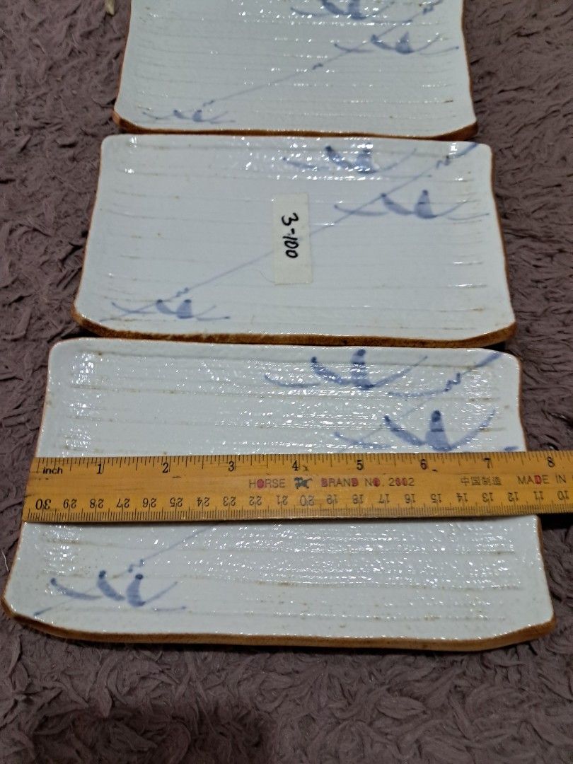 Suzhi plate set (Category: Dinnerware & Cutlery) located in Cavite. Submitted by secretjapansurplus (Listing ID 1469987815, Image 2). Description: Vintage Japanese Rectangular Ceramic Plates (Set of 3) • Design: Beautifully handcrafted with a rustic, textured white-cream glaze (awayuki style) and elegant, hand-painted cobalt blue underglaze grass motifs. Features a traditional unglazed brown clay trim along the edges. • Size: Approximately 8 inch