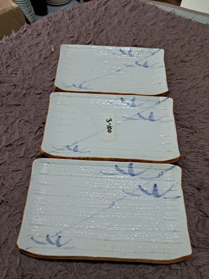 Suzhi plate set (Category: Dinnerware & Cutlery) located in Cavite. Submitted by secretjapansurplus (Listing ID 1469987815, Image 1). Description: Vintage Japanese Rectangular Ceramic Plates (Set of 3) • Design: Beautifully handcrafted with a rustic, textured white-cream glaze (awayuki style) and elegant, hand-painted cobalt blue underglaze grass motifs. Features a traditional unglazed brown clay trim along the edges. • Size: Approximately 8 inch