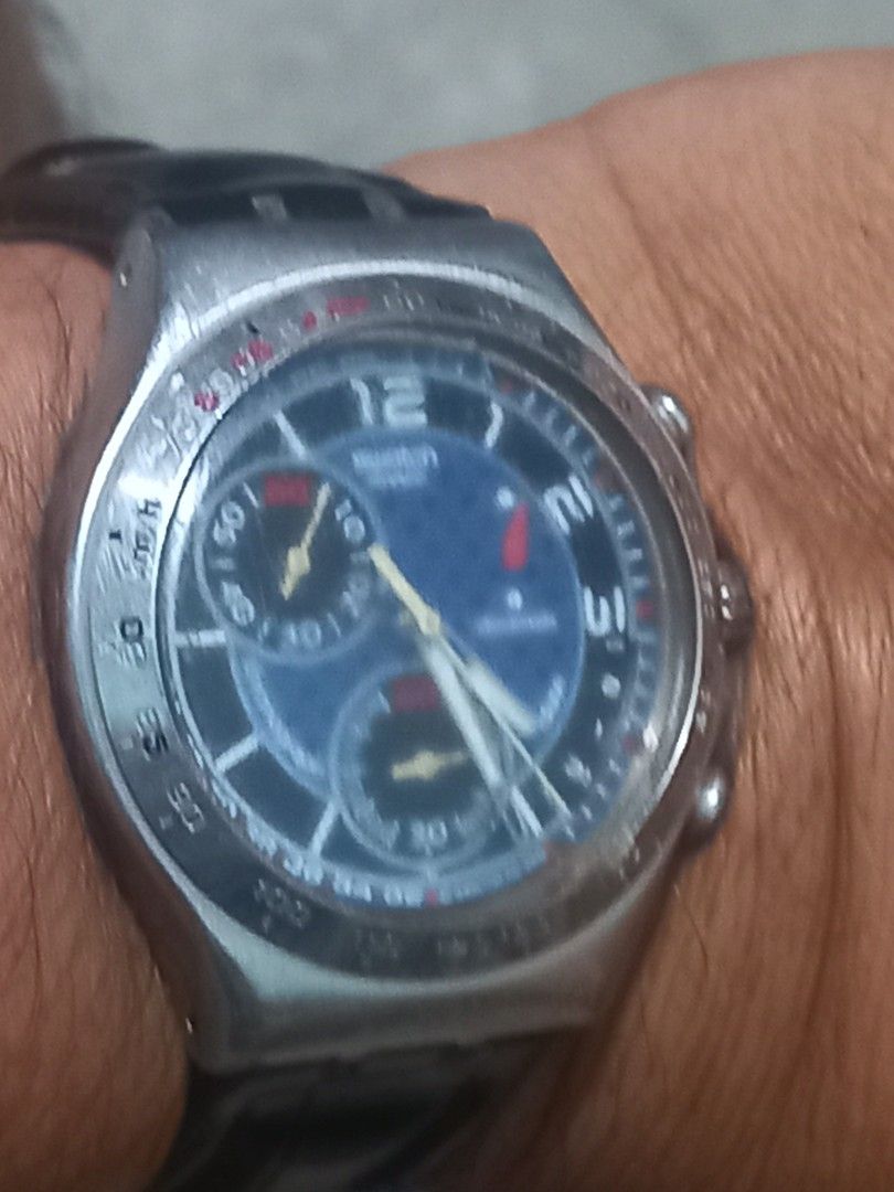 Swatch Chronograph Watch Blue Dial Leather Strap (Category: Men's Watches) located in Subic. Submitted by regiegabriel29 (Listing ID 1470030032, Image 3). Description: - Brand: Swatch Chronograph - Dial: Blue patterned face with large numbers (12, 1, 2, 3) and three sub-dials with vibrant yellow hands - Case & Bezel: Silver-tone metal case equipped with a tachymeter bezel - Strap: Black leather strap with standard metal buckle clasp - Condition: 