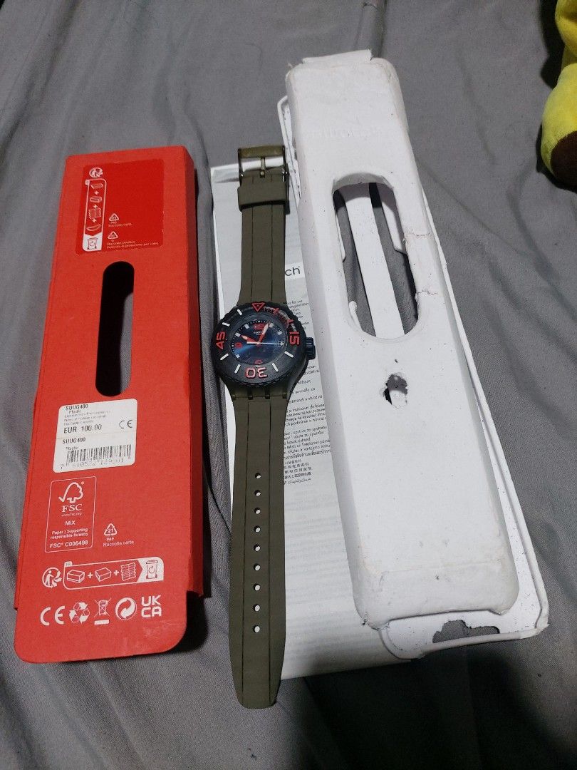 Swatch SUUG400 Swiss Made Plastic Watch (Category: Women's Watches) located in Manila. Submitted by kenriosy (Listing ID 1470049564, Image 3). Description: - Brand: Swatch (Swiss Made) - Model: SUUG400 - Design: Blue dial with vibrant red numbers and hands, paired with a green strap - Condition/Inclusions: Complete with original red packaging box, plastic holder case, and instruction booklet - Price Tag: Original 100 EUR retail tag still attached