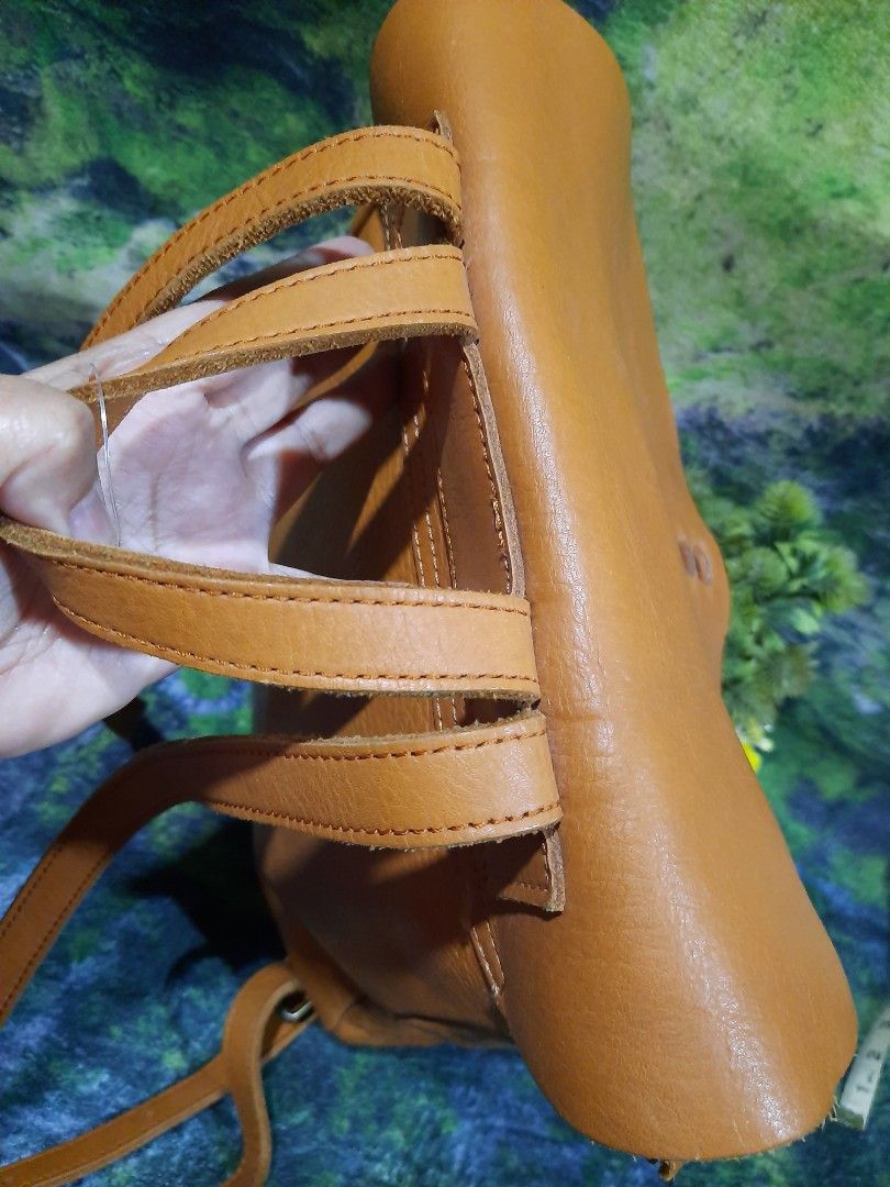 Tan Brown Leather Backpack Drawstring Flap Bag 13x12 (Category: Backpacks) located in Baguio. Submitted by klayblakeb87803 (Listing ID 1470060116, Image 3). Description: - Color: Classic tan brown - Material: Soft leather texture - Closure: Flap with leather drawstring and knot detail - Carry options: Adjustable shoulder straps and top carry handle - Dimensions: Roughly 13 inches high and 12 inches at the base - Interior: Roomy main compartment f